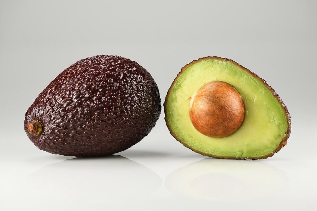 Un avocado tagliato a metà, una parte vista da fuori, una da dentro con polpa e seme